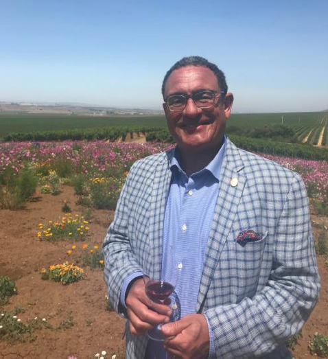 master sommelier thomas price standing in vineyard with glass of wine