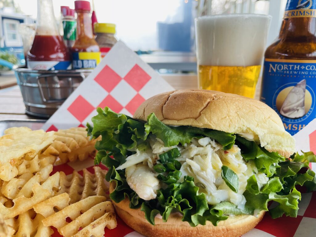 crab sandwich with a side of waffle cut fries and a micro beer