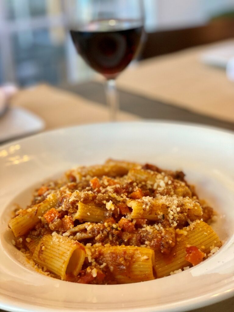gourmet itlian bolognese pasta with a glass of red wine