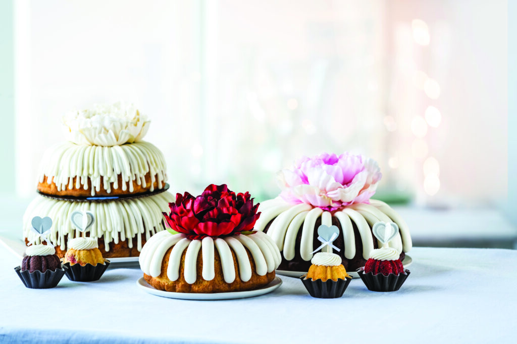 Nothing Bundt Cakes. Large and mini bundt with icing cakes arrange on a table with flower decor.